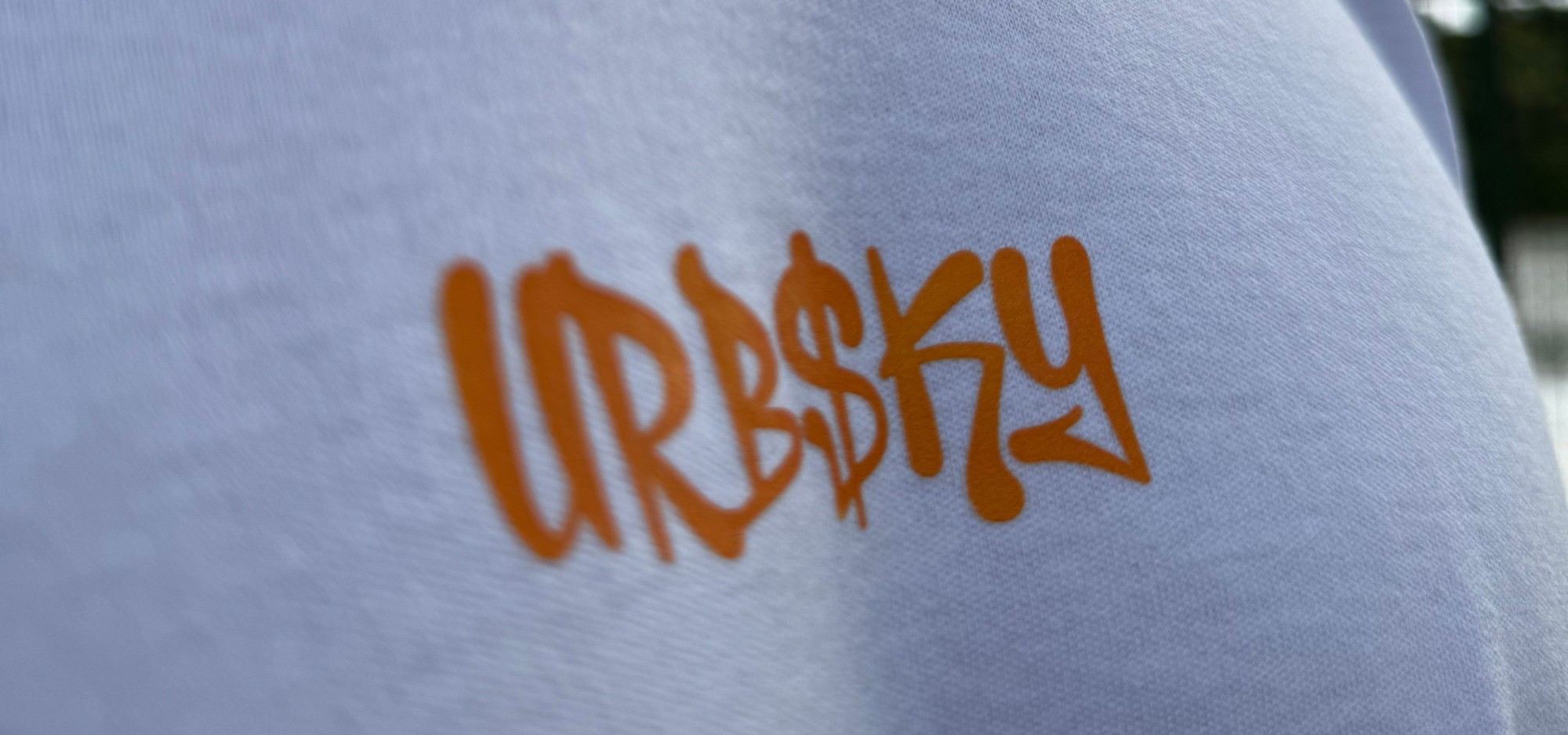 Close da estampa URBSKY em laranja sobre o tecido